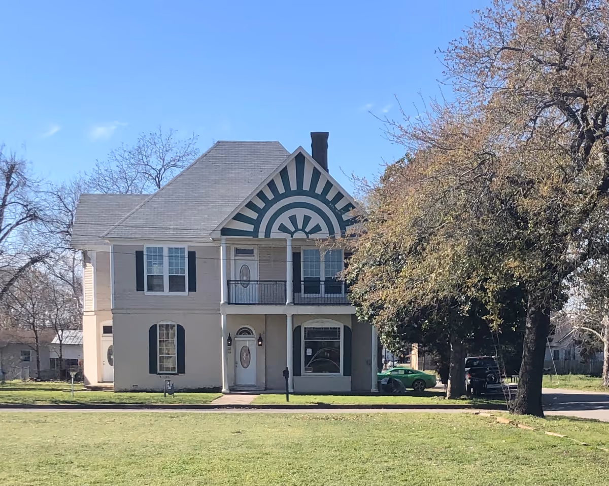 Two-story house-style senior living facility with teal sunburst front.