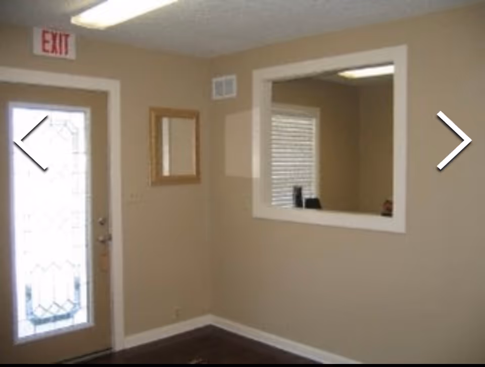 Entryway interior with an exit door, pass-through window, beige walls, and a mirror.