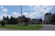 Front exterior of Thornwald Home with a green lawn, circular drive, and blue sky.