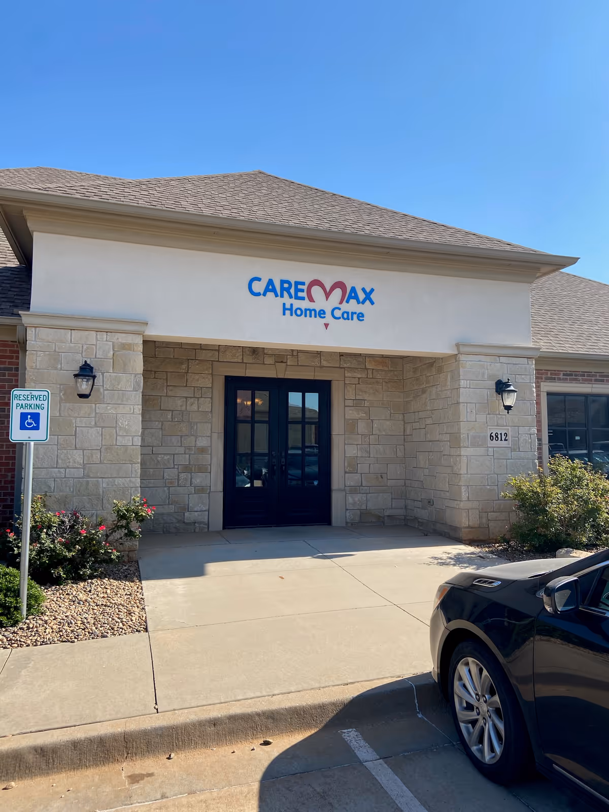 CareMax Home Care building entrance with stone facade and clear blue sky.