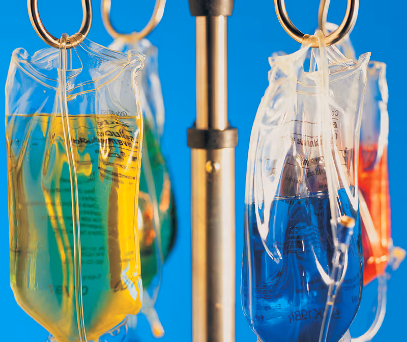 Close-up of colorful IV bags hanging on a medical stand.