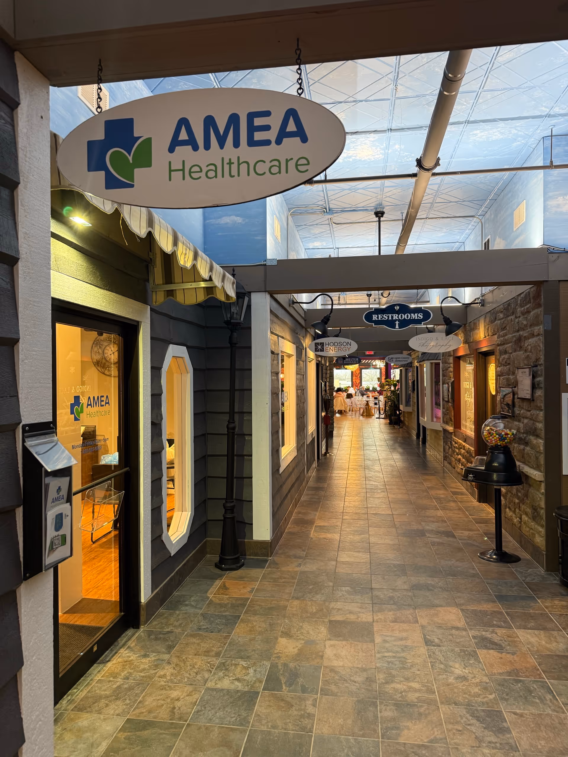 An indoor corridor of AMEA Healthcare with storefront doors and restroom signs.