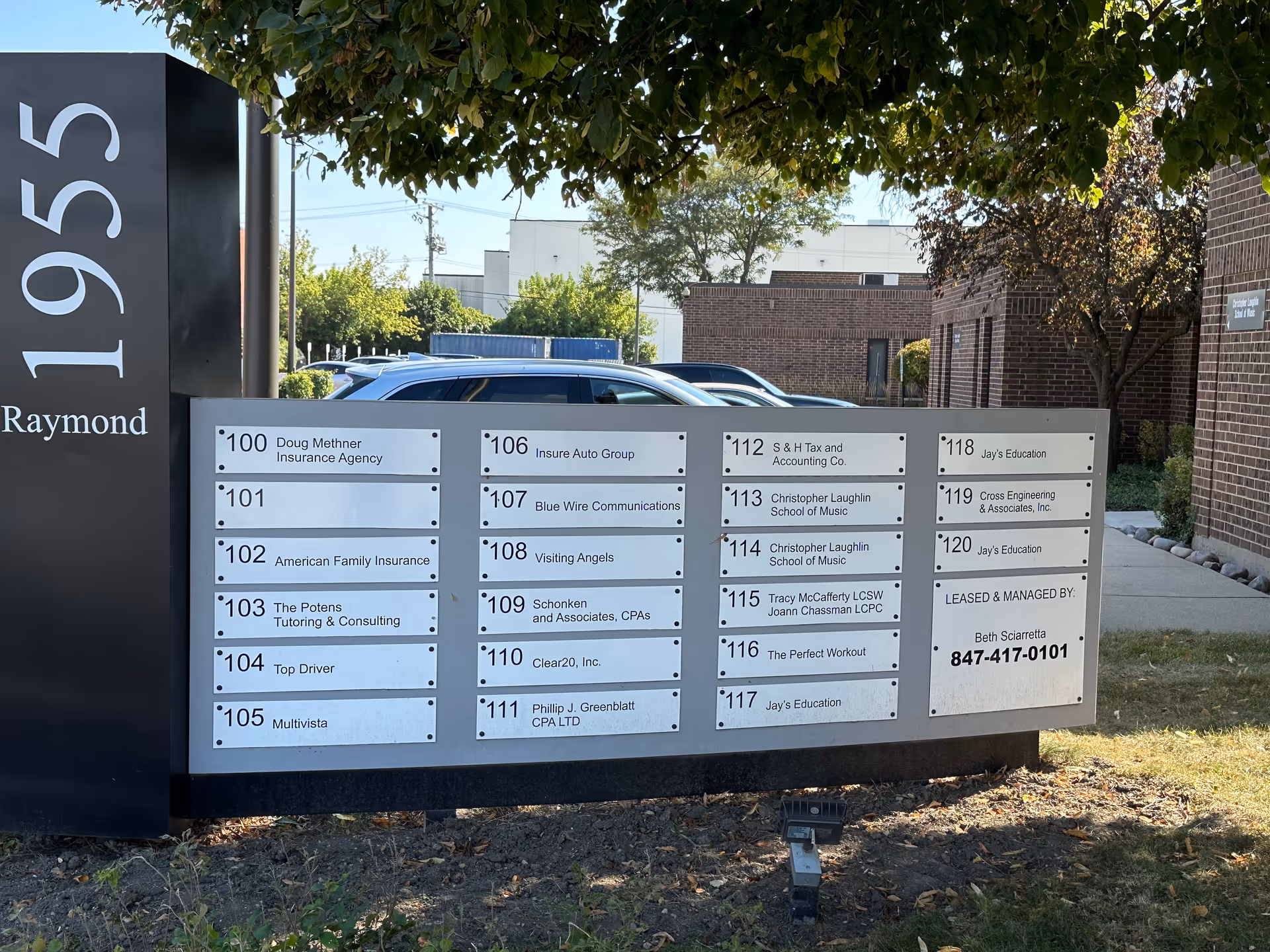 Outdoor building sign with directory plaques listing office suites.