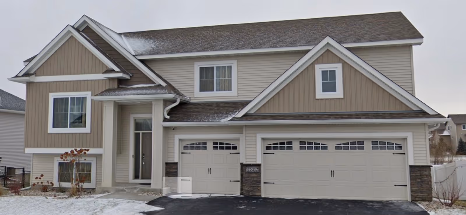 Two-story beige senior living facility with front entry and three-car garage.