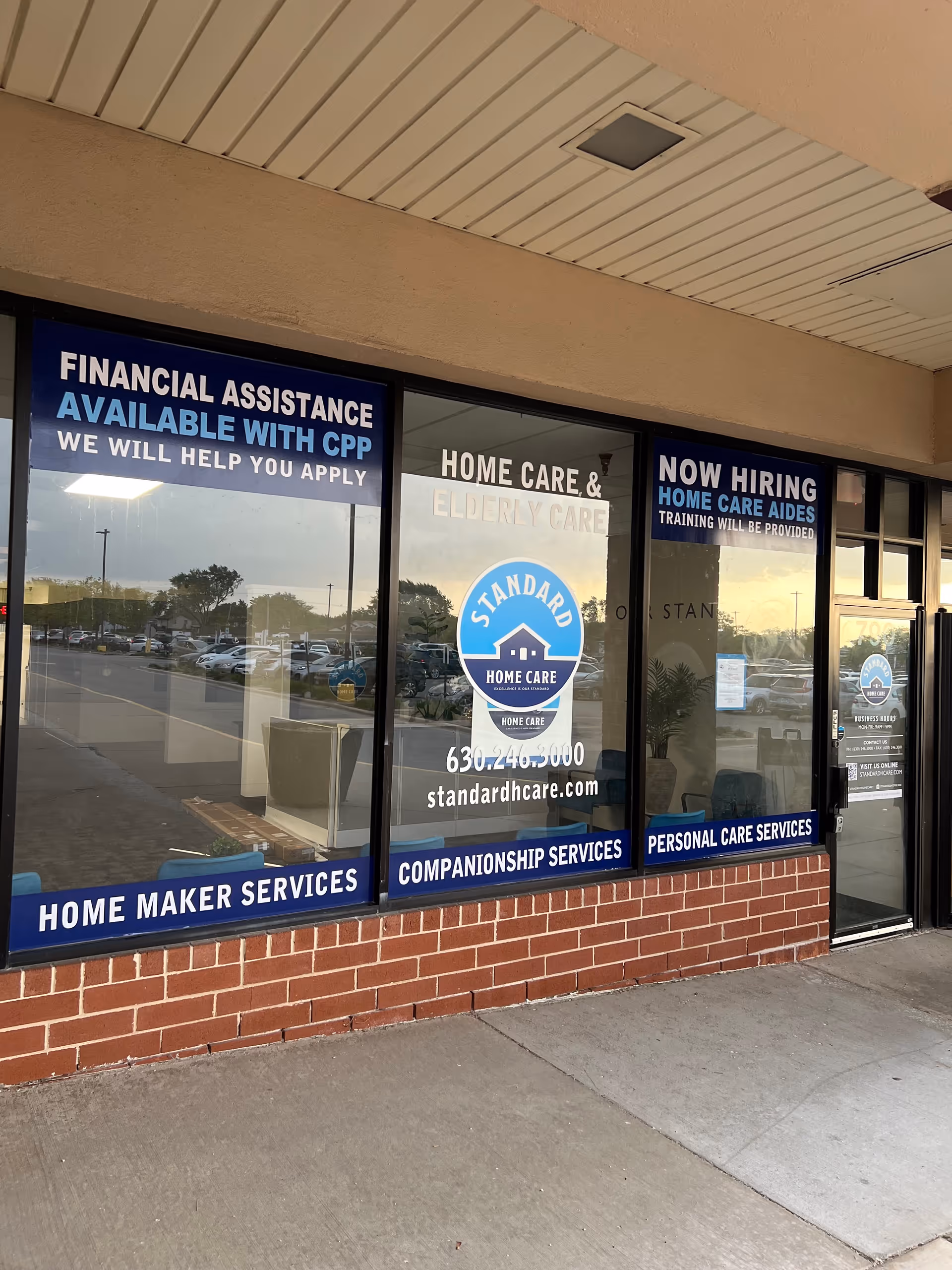 Exterior storefront with large windows displaying Standard Home Care services and hiring information.