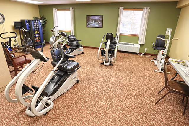 An interior senior living facility gym with treadmills and stationary bikes.
