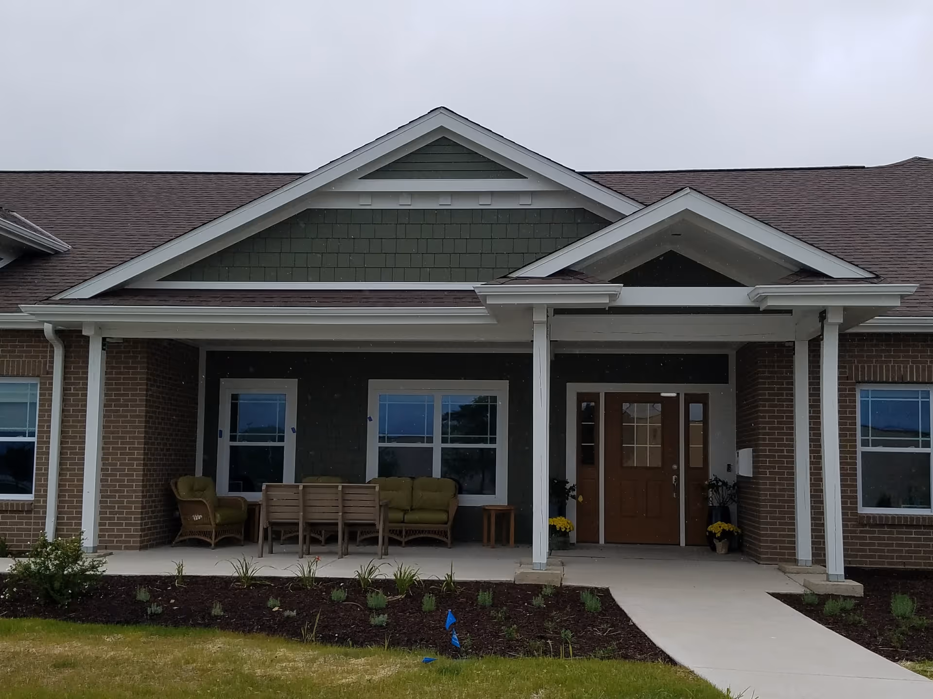 Front exterior of Highland Oaks facility with a covered porch and outdoor seating.