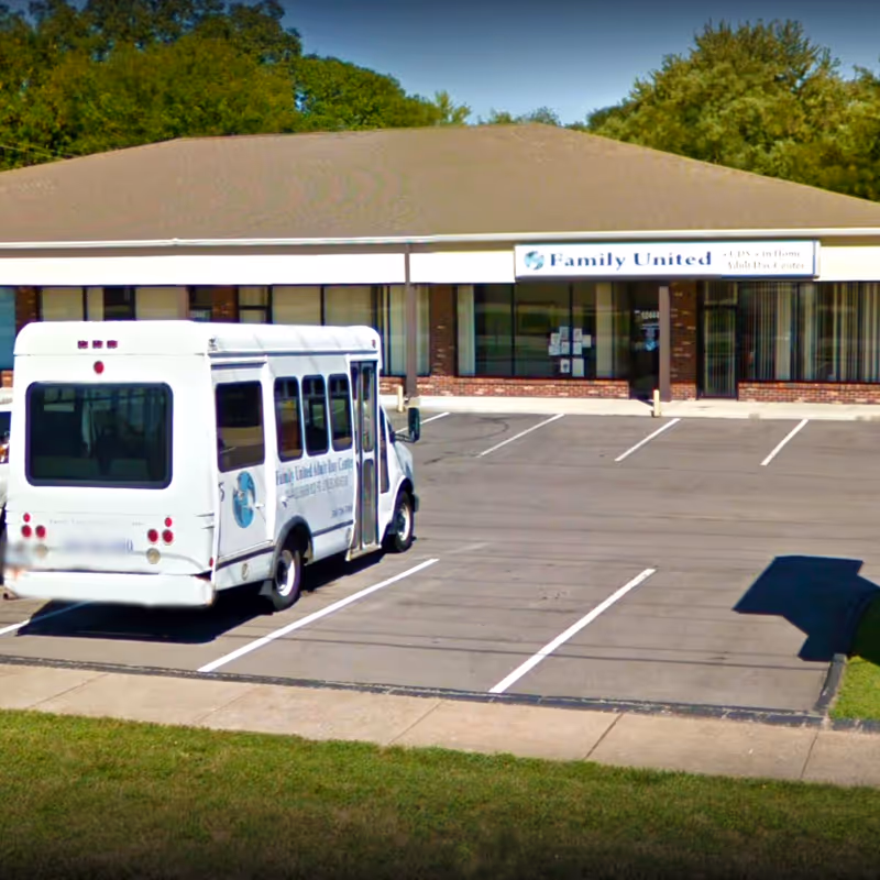 White shuttle bus parked in front of a Family United Home Healthcare facility.