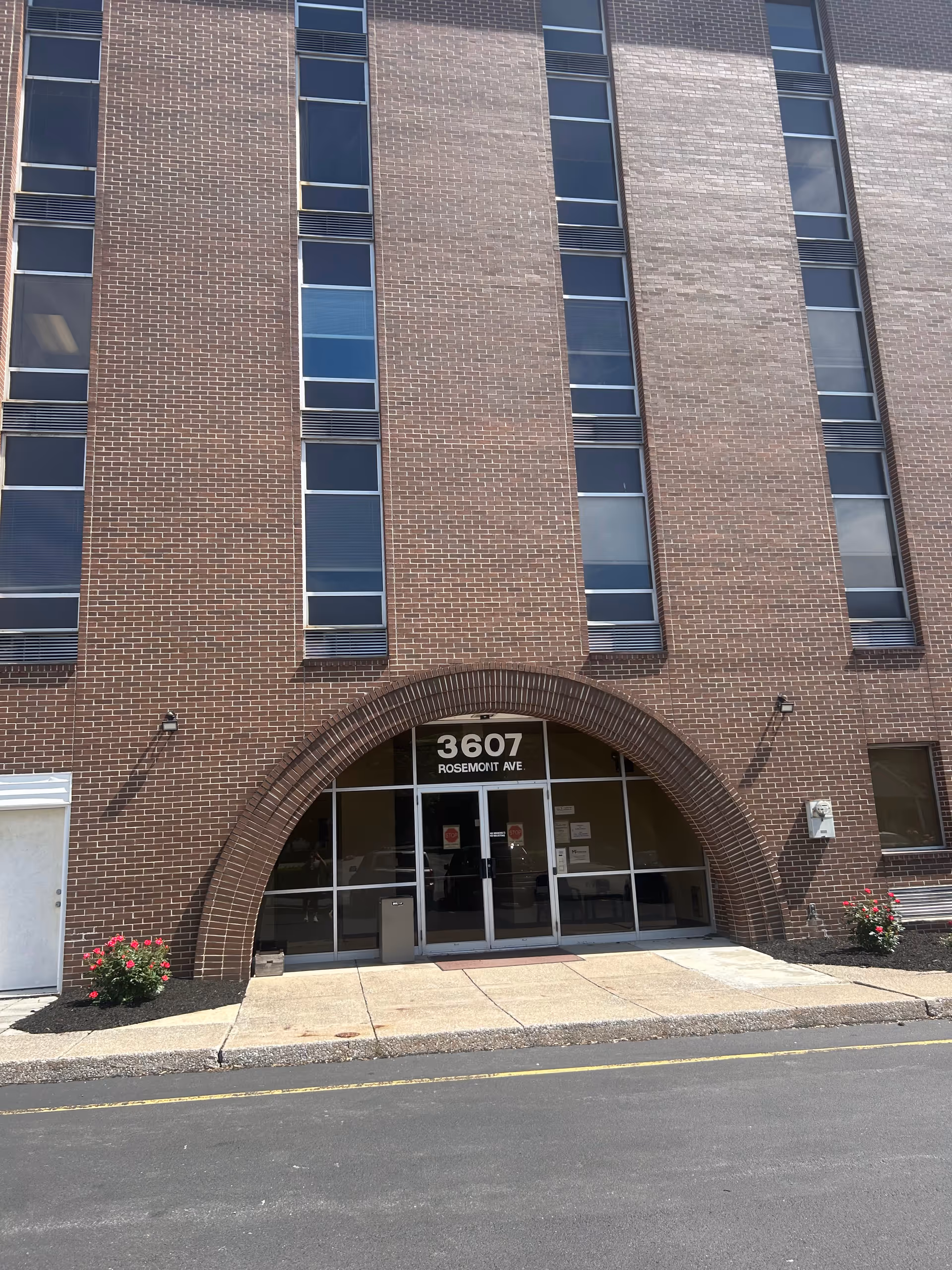 Brick building exterior featuring arched entrance with glass doors and address 3607 Rosemont Ave.