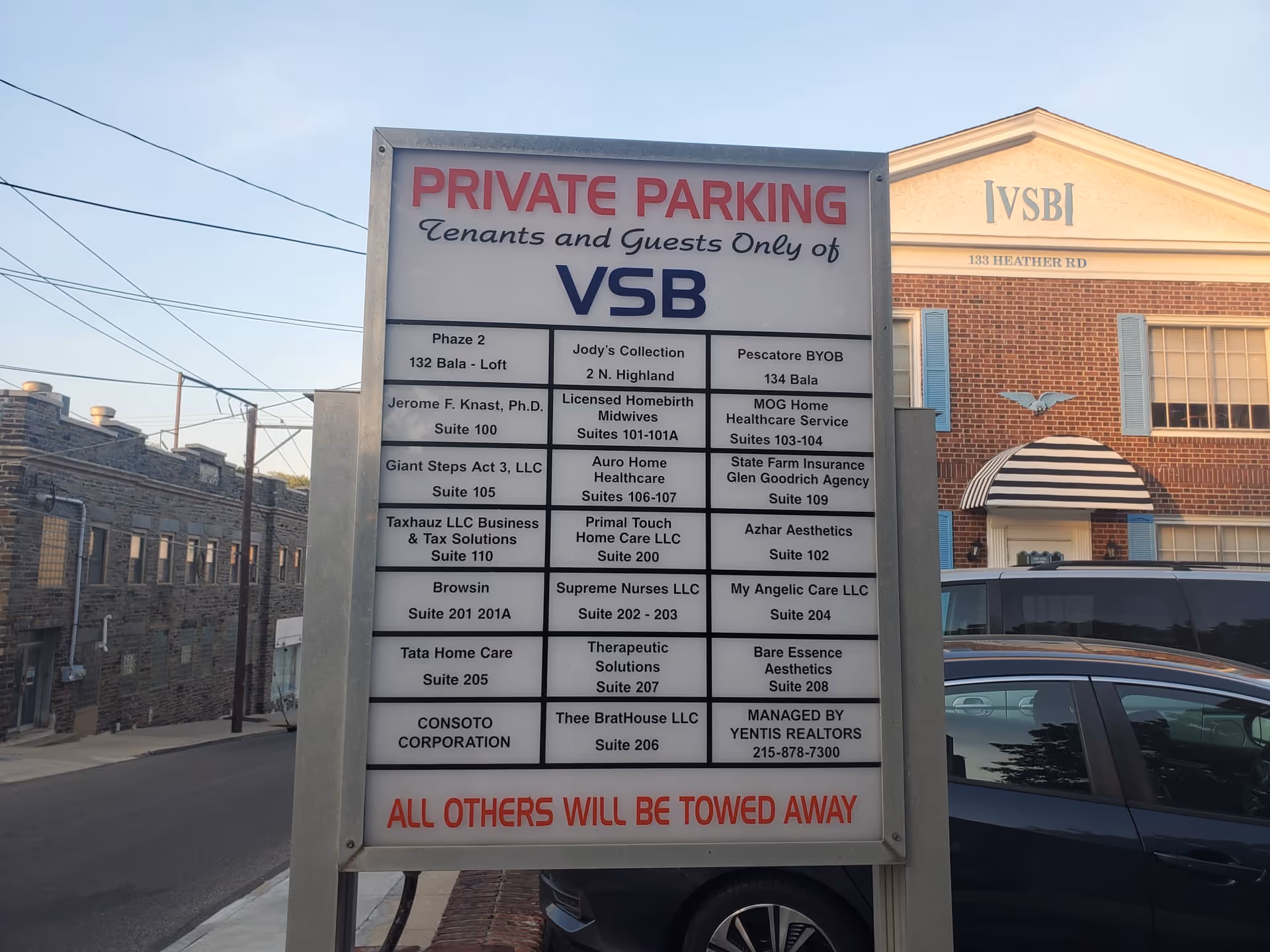 A large private parking sign for tenants and guests near a brick building.