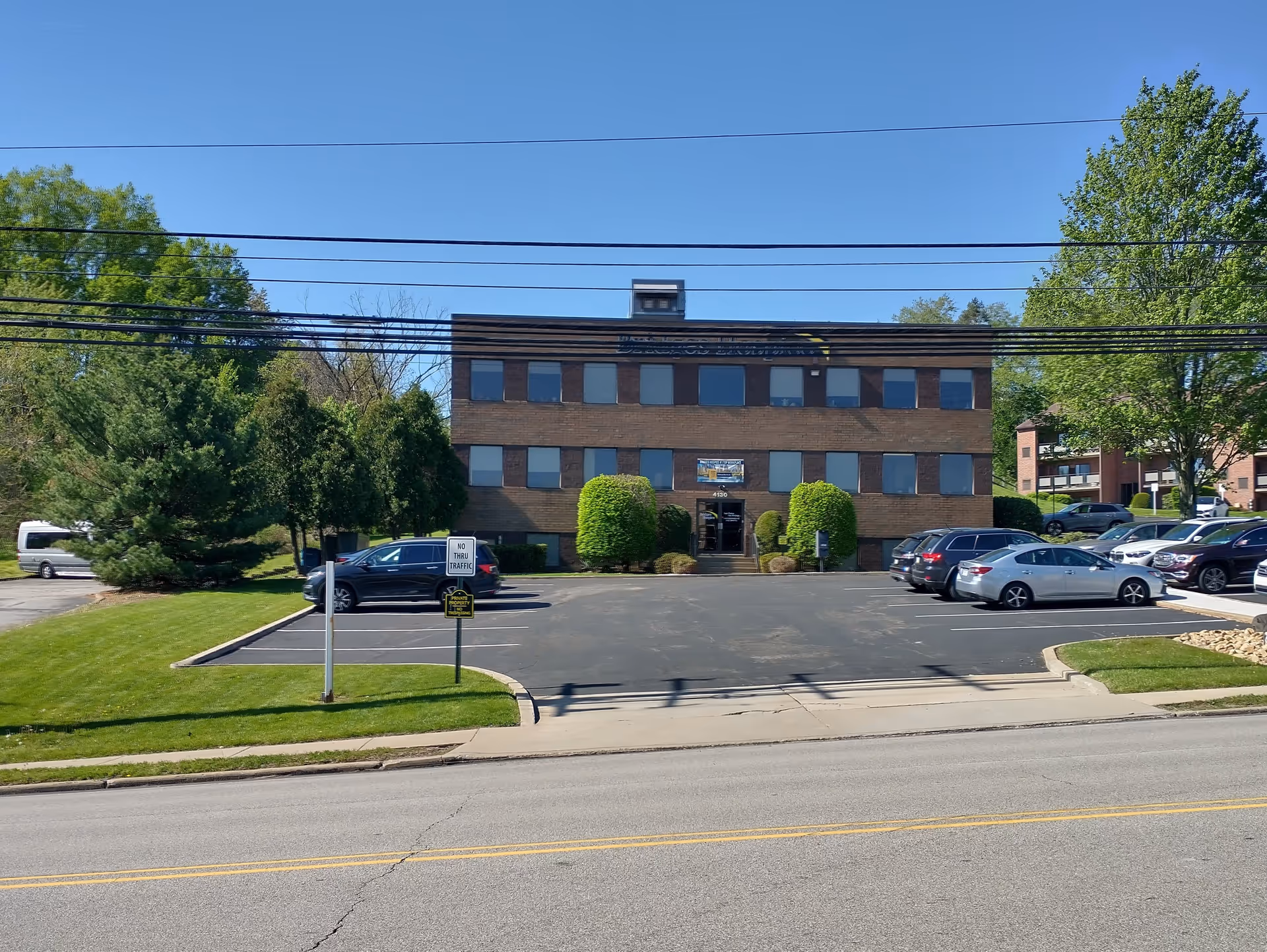 Exterior view of a brick three-story facility with a parking lot in front.