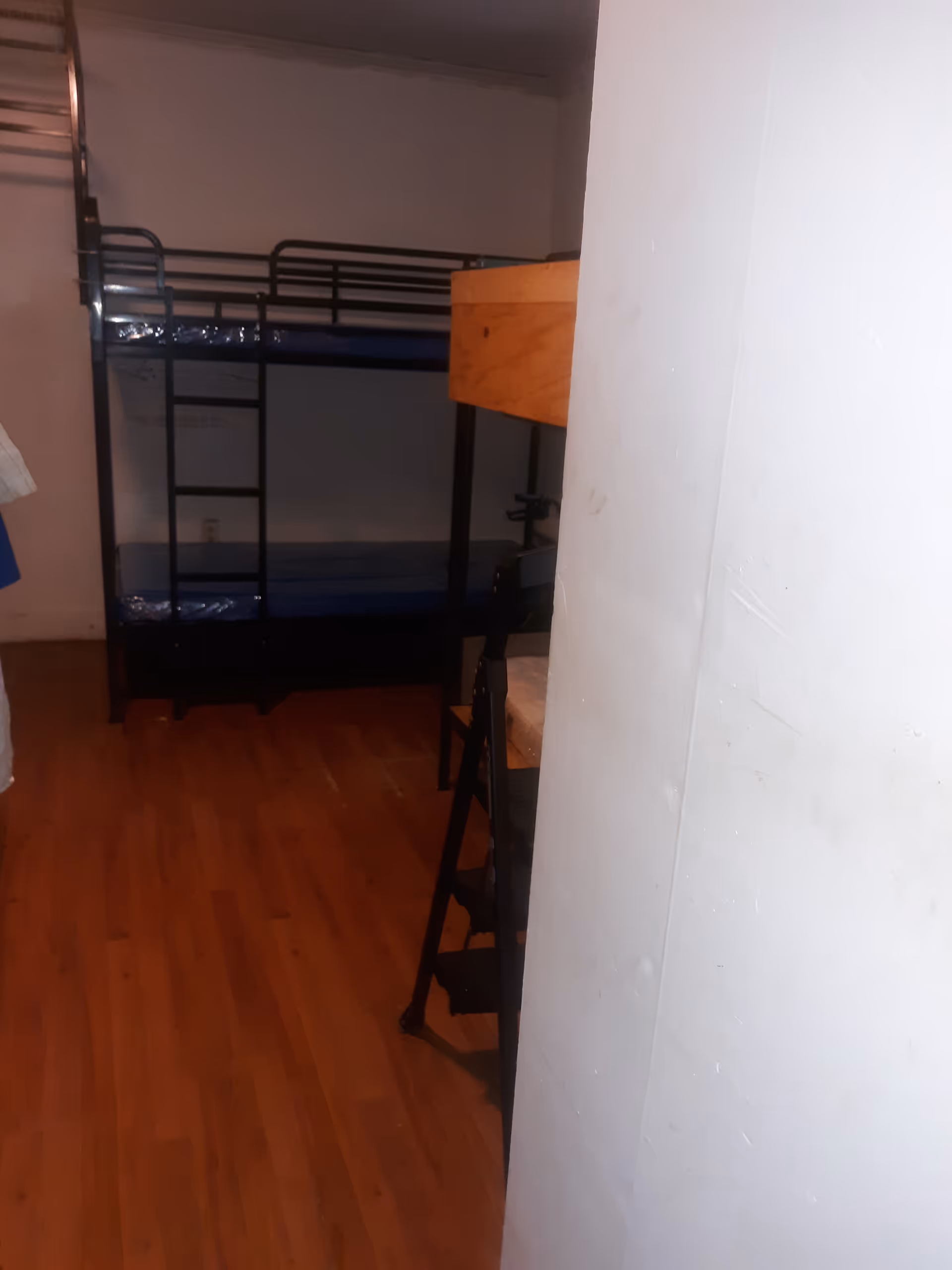 Interior bedroom with metal bunk beds, wooden floor, and a partially obscuring white pillar.