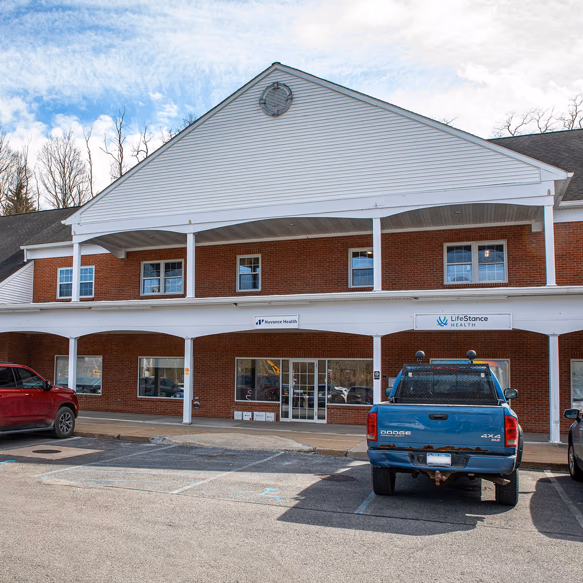 Front view of a brick medical practice with a covered entrance and parked cars.