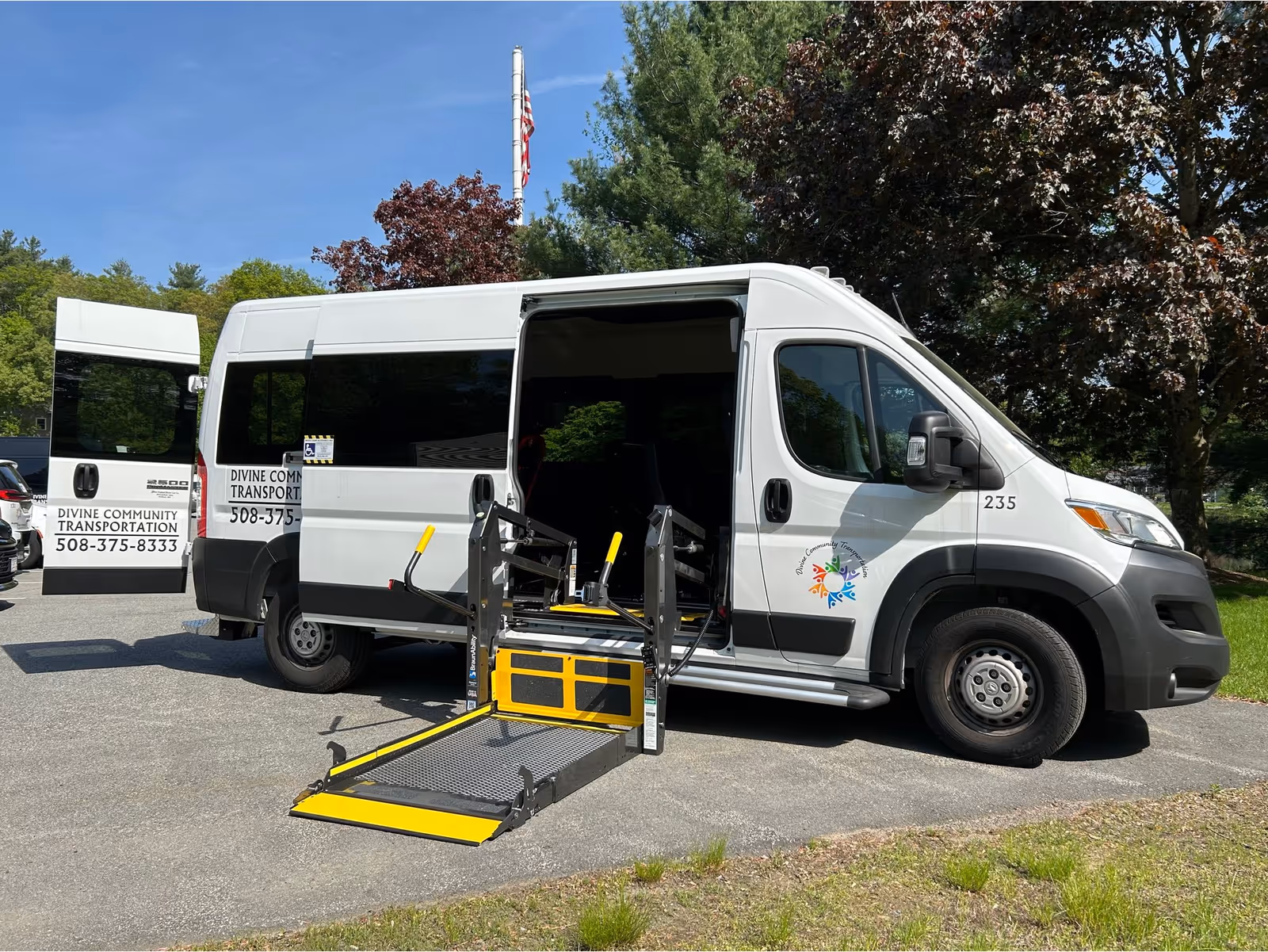 White van labeled Divine Community Transportation with a yellow wheelchair ramp in a parking lot.