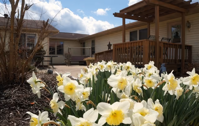 Exterior view of Sycamore House Independent Living with a wooden deck and blooming daffodils.