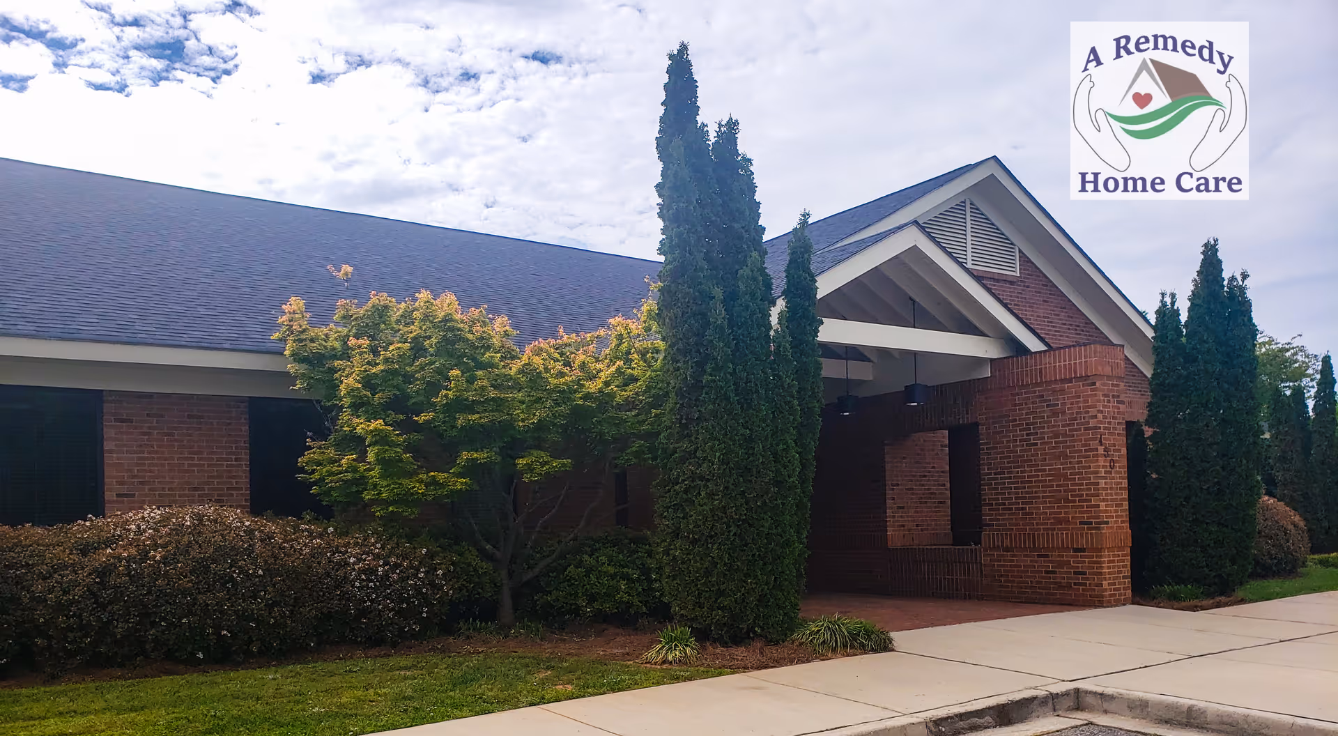 Exterior brick senior care facility with a covered entrance and surrounding trees.