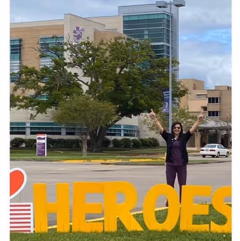 Person stands outdoors by large HEROES sign in front of Christus Hospice St. Frances Cabrini.
