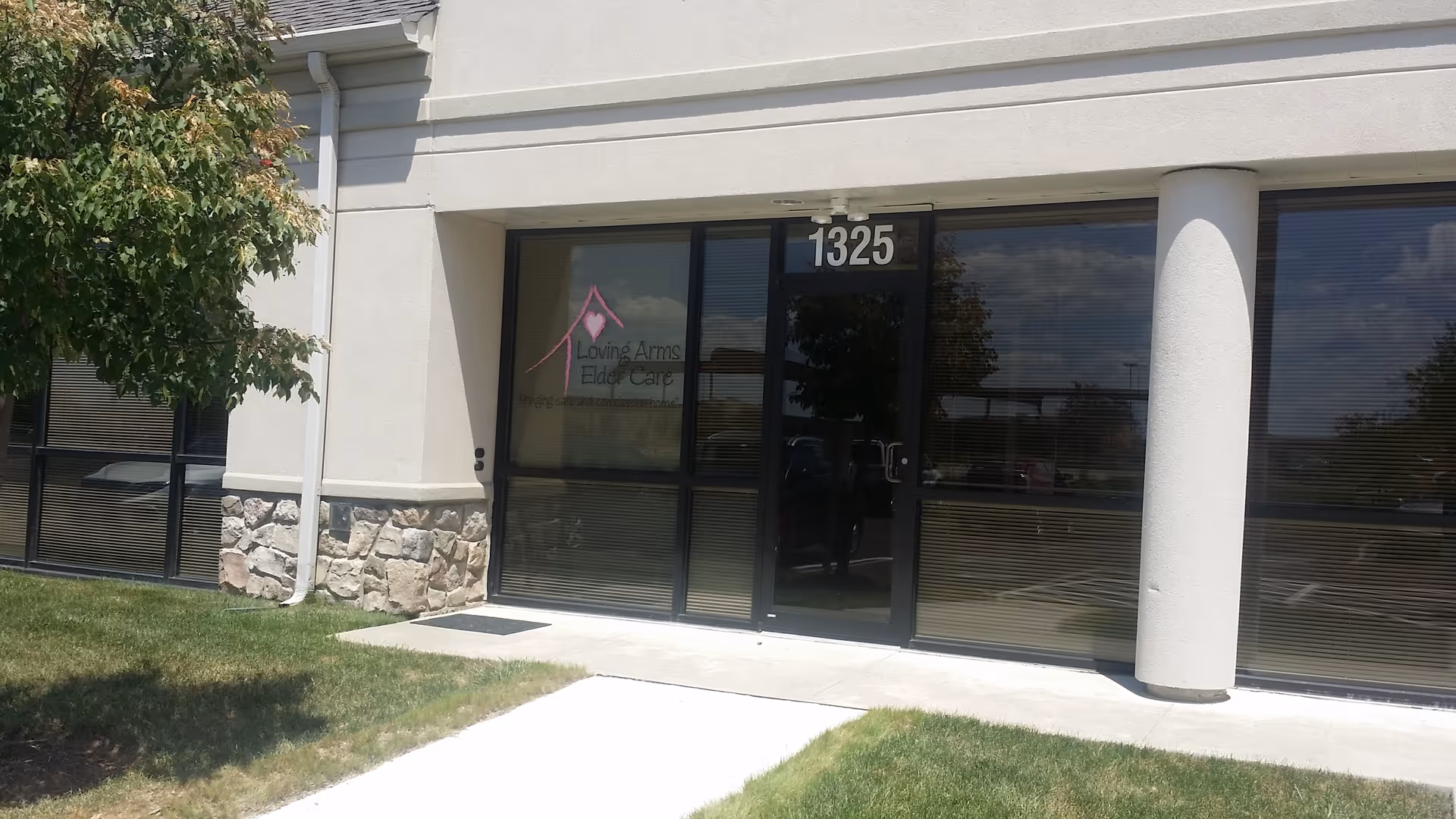 Exterior view of Loving Arms Elder Care entrance with glass doors and address 1325.