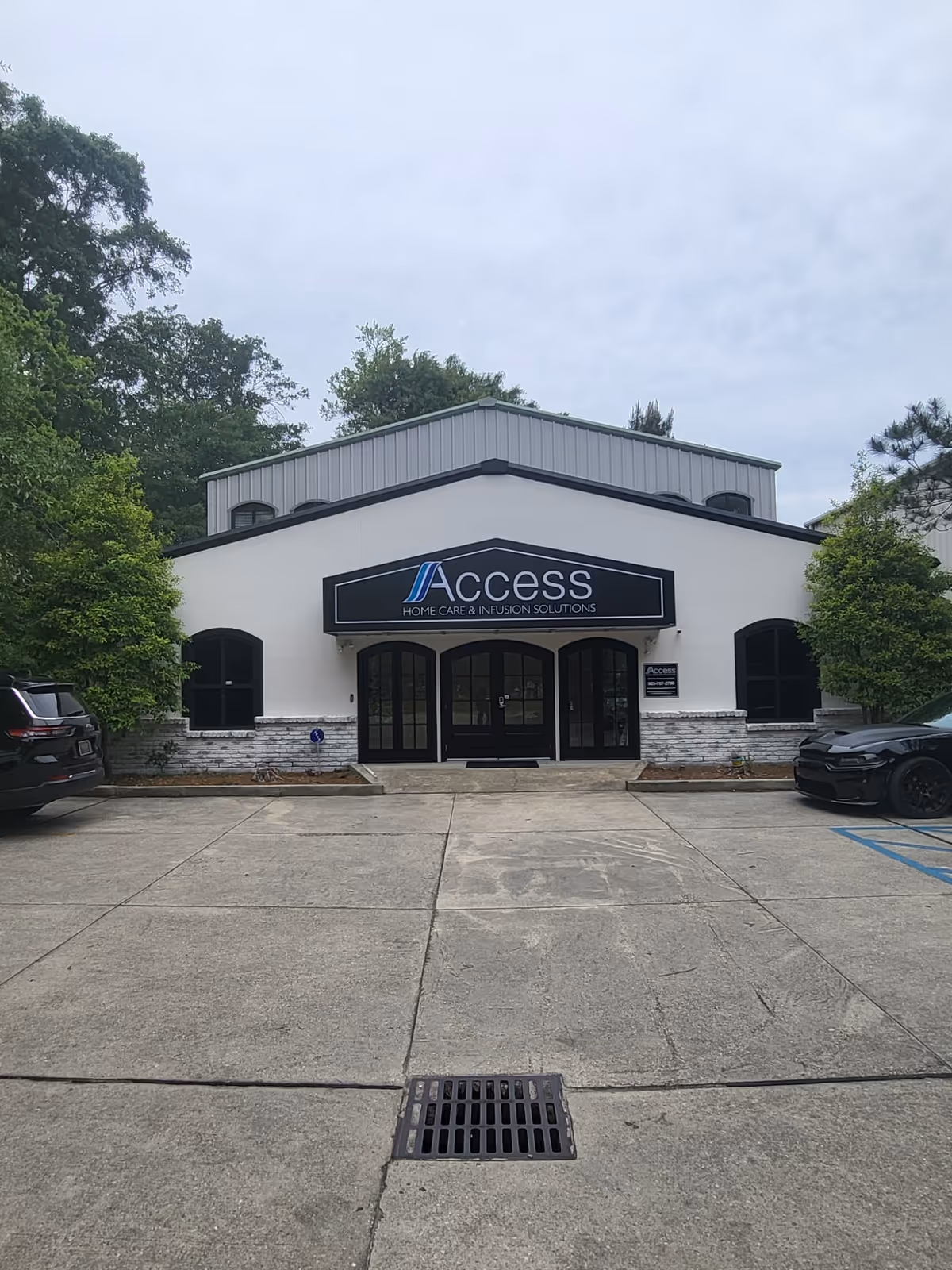 Front view of Access sign on Home Care & Infusion Solutions building with parked cars.