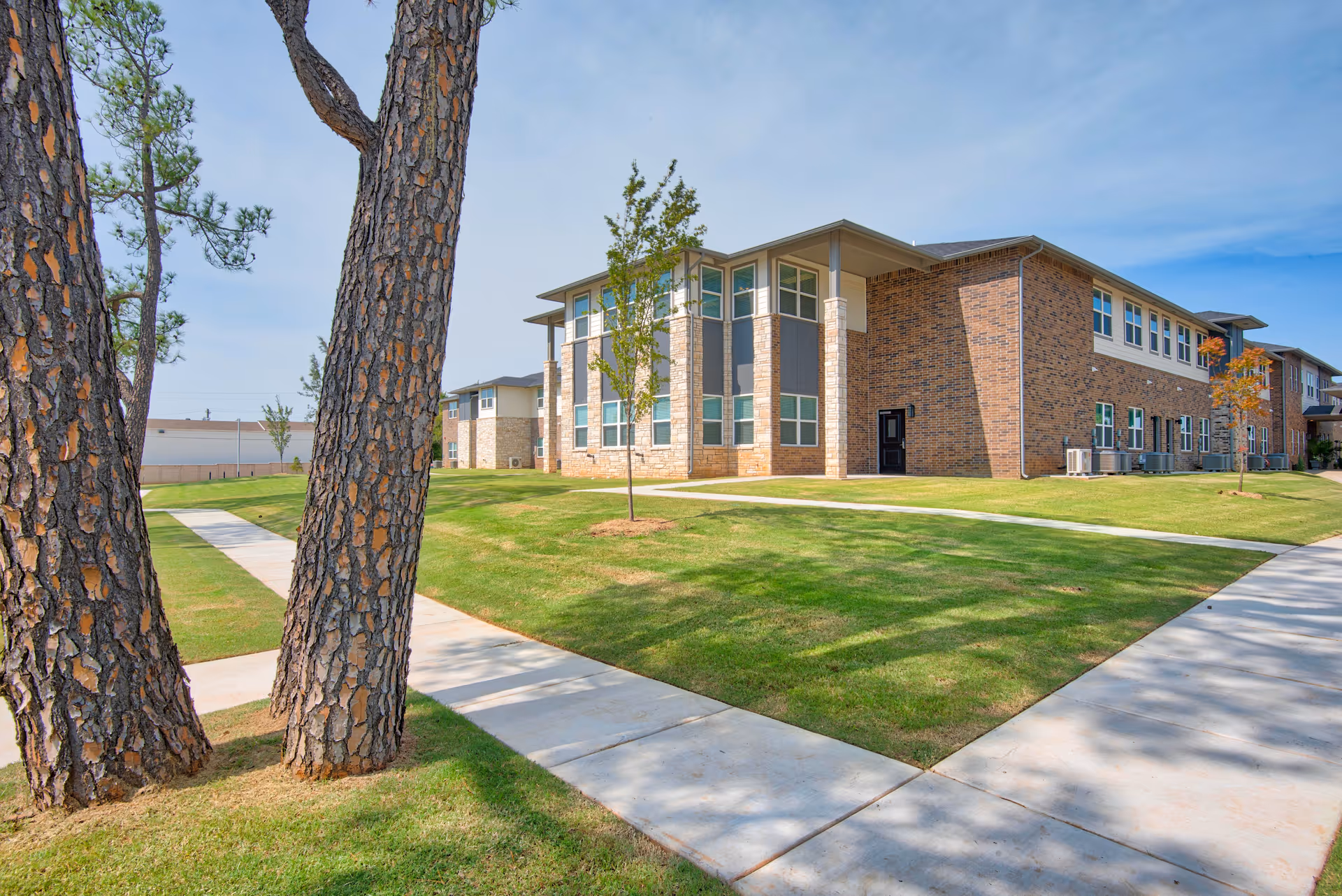 Exterior view of Carlstone Active Adult Living Community building with brick walls and green lawn.