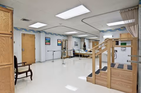 Interior rehabilitation room with gait training bars and seating in a ProMedica facility.