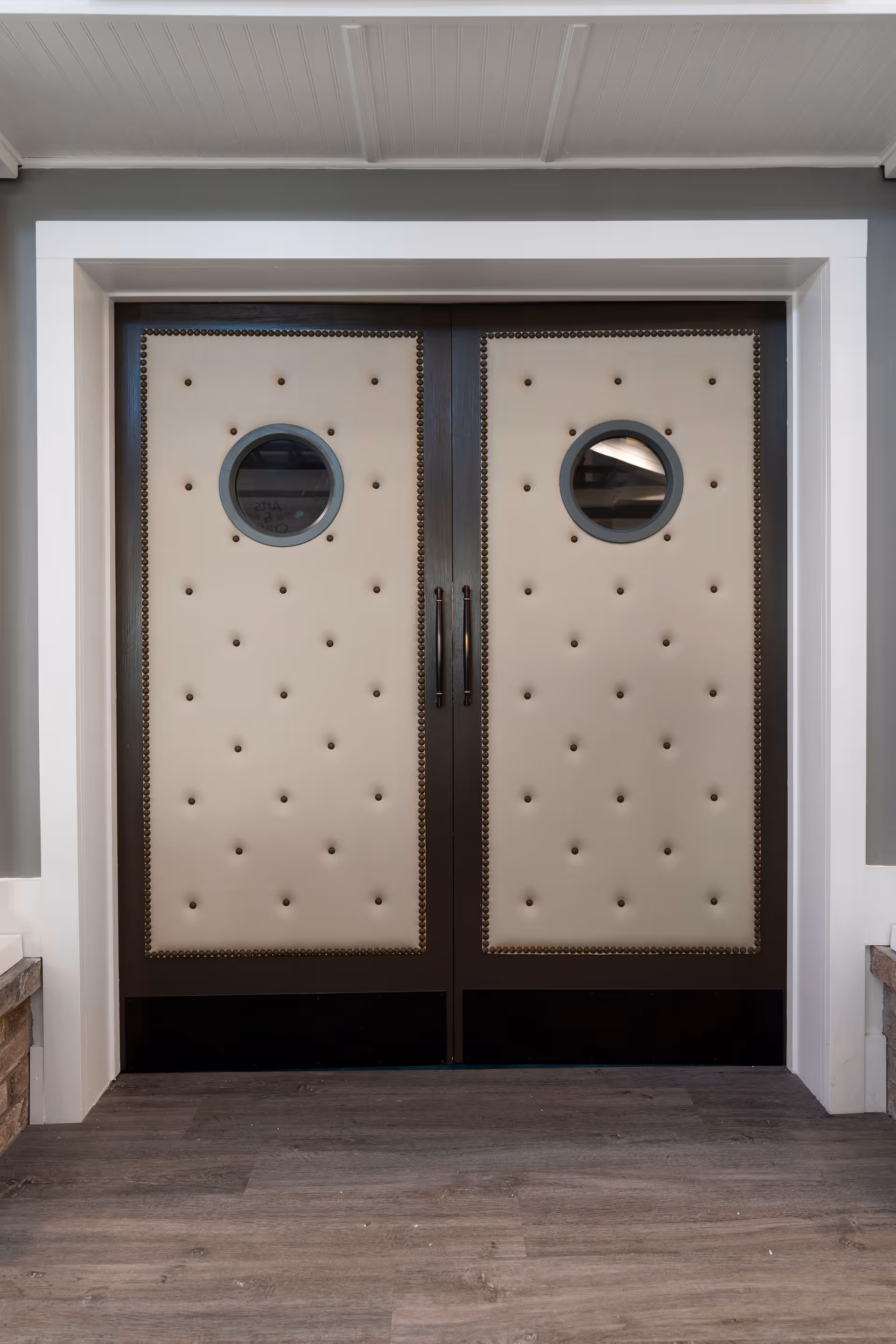 Double beige tufted doors with round windows frame the building entrance.