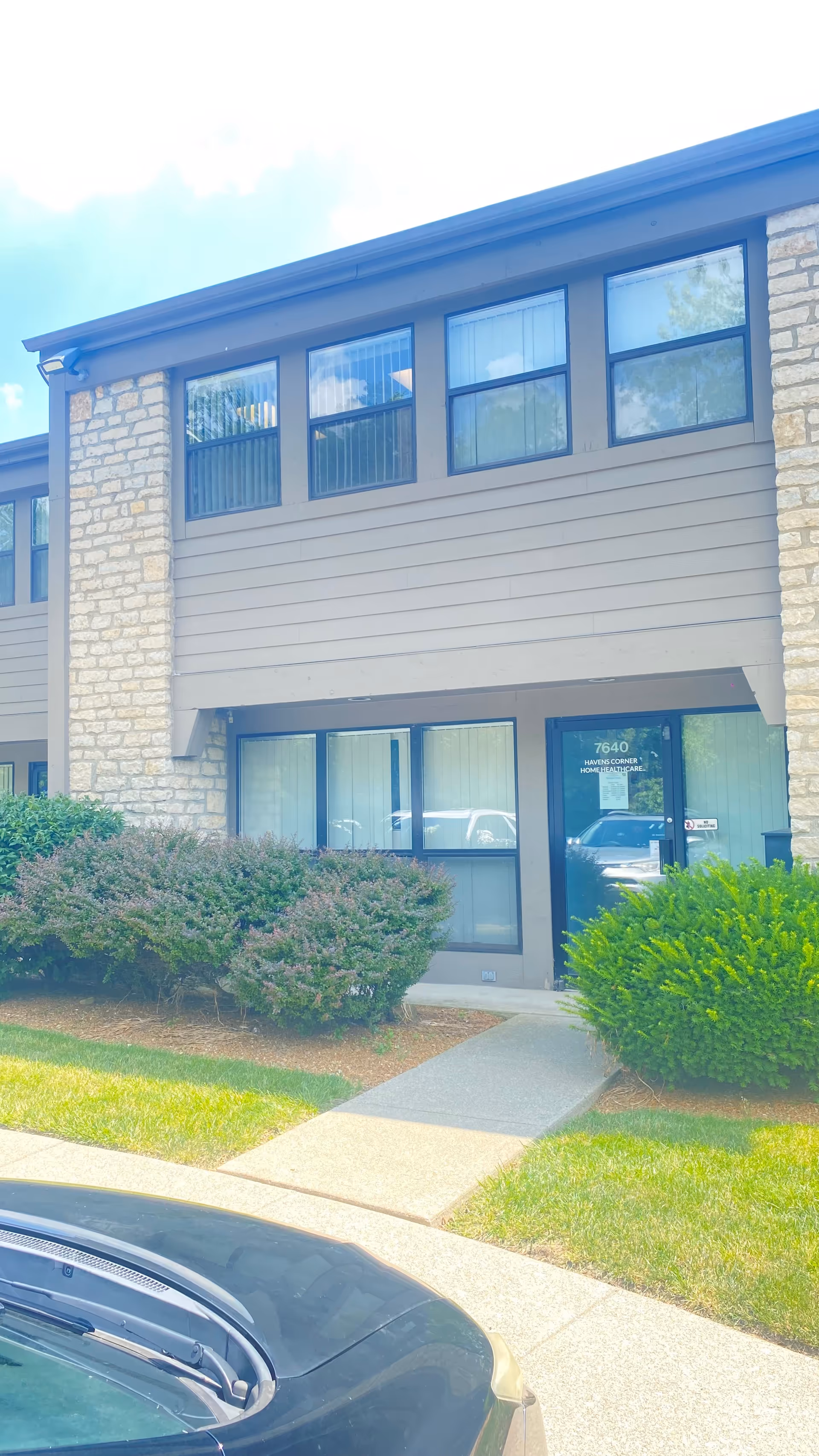 Exterior view of HavensCornerHomeHealthcare building with entrance, shrubs, and a parked car.