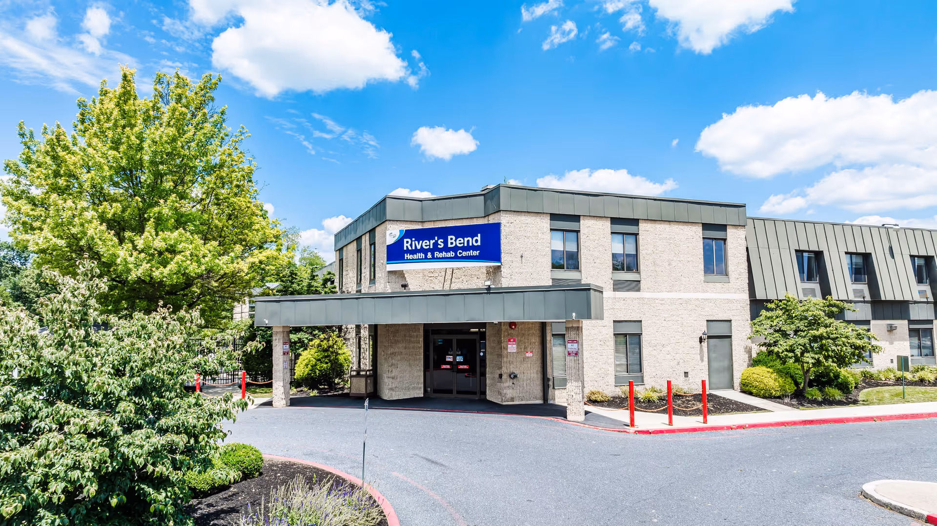Exterior view of River's Bend Health Rehab Center under a blue sky.