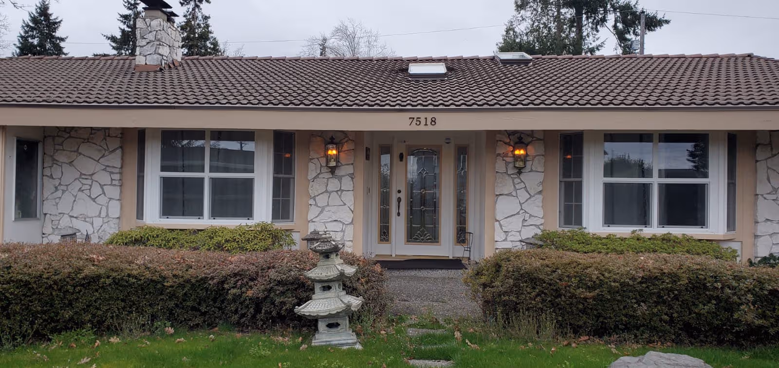 Front view of a single-story senior living home with stone accents and hedges.