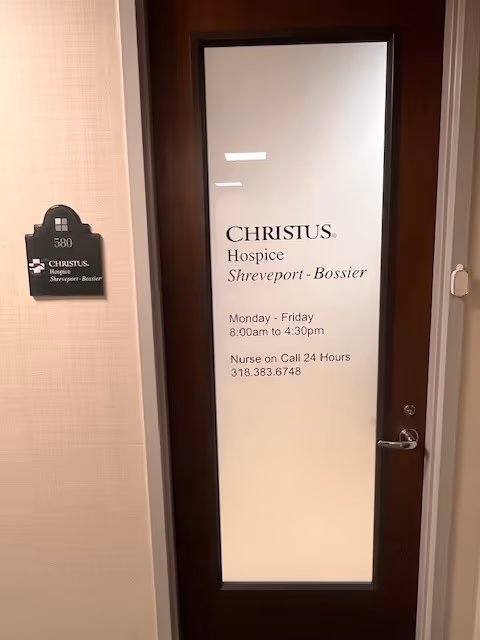 Frosted glass door with CHRISTUS Hospice Shreveport-Bossier sign in a hallway.
