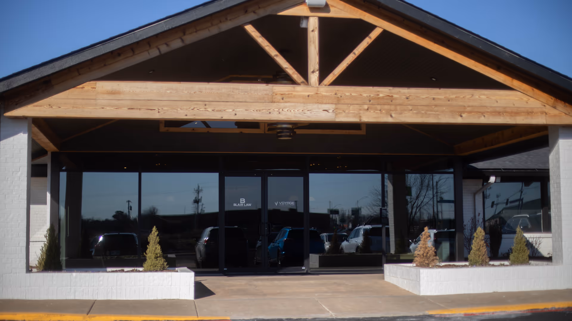 Exterior view of a Voyage Long Term Care building front with glass doors and wooden porch.