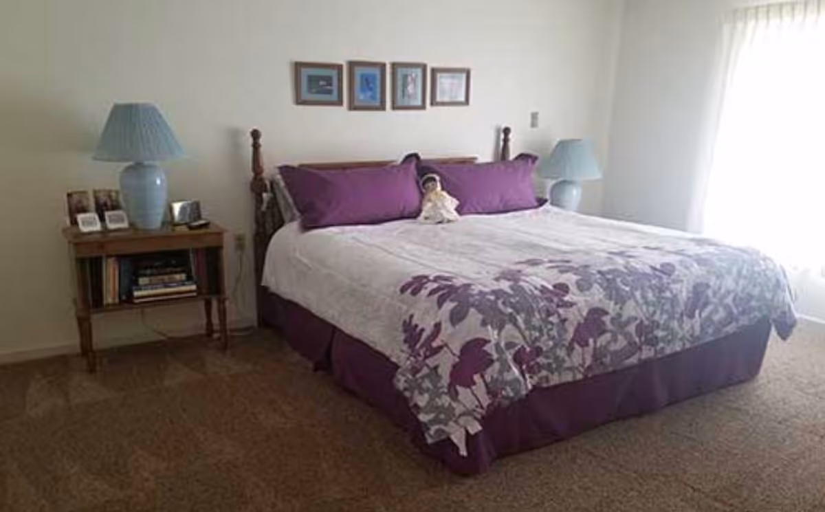 A well-made bedroom with a large bed, purple accents, lamps, and nightstands.