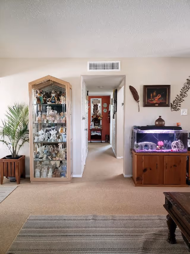 Hallway in a senior living home with display cabinet, aquarium, and decor.