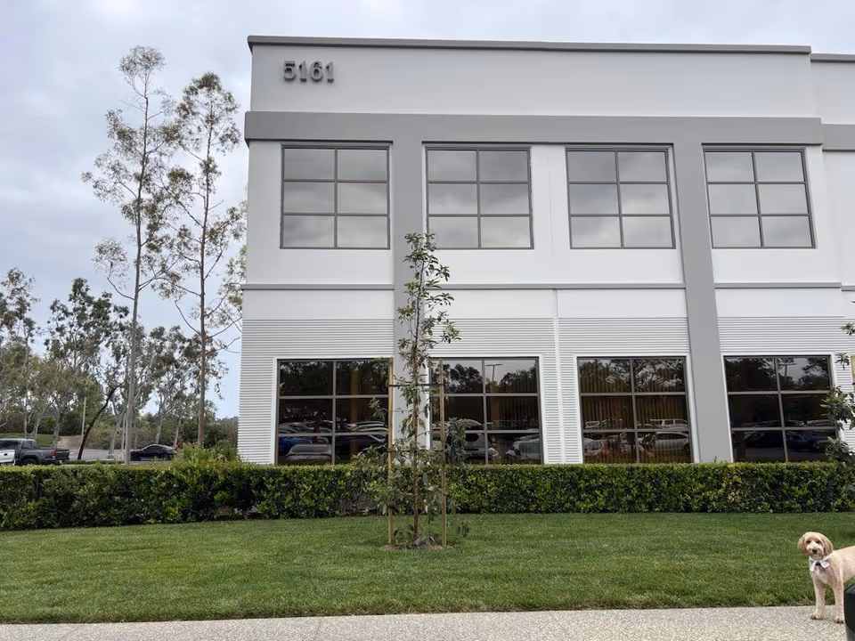 Exterior view of Care Partners At Home facility with windows, trees, and a dog in foreground.