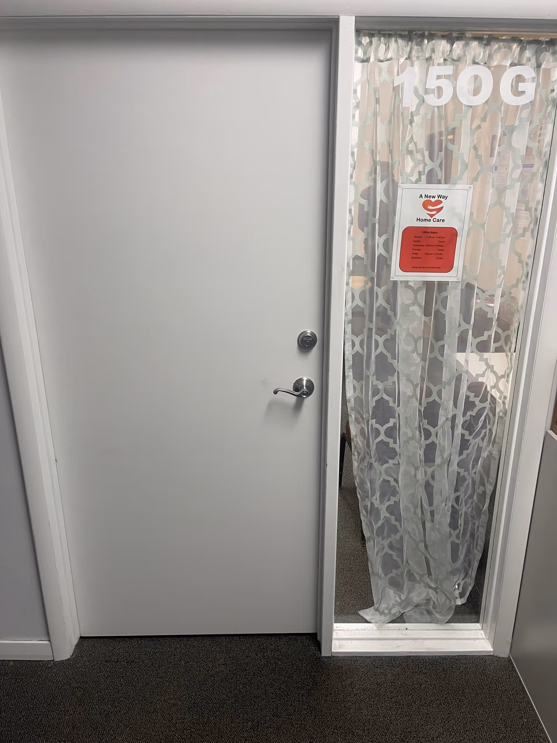 Gray interior door beside sheer patterned curtain and a red A New Way Home Care sign.