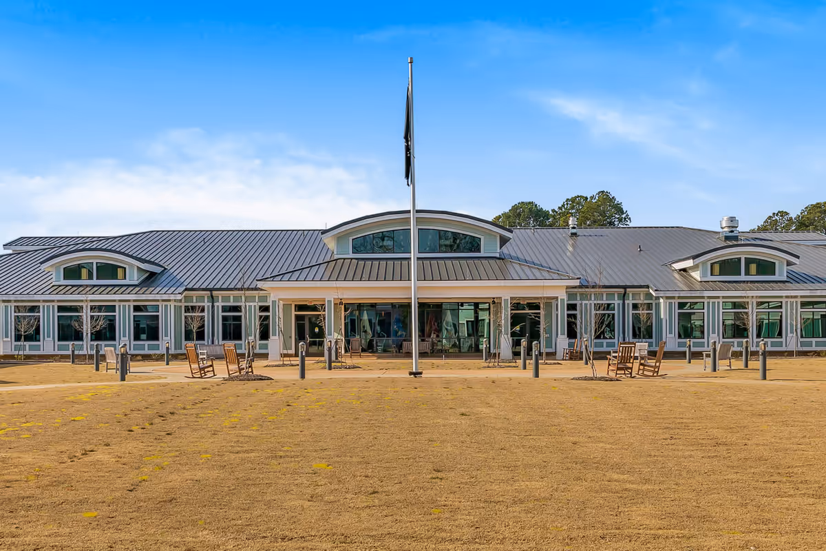 Long single-story facility with glass entrance, flagpole, and seating outside