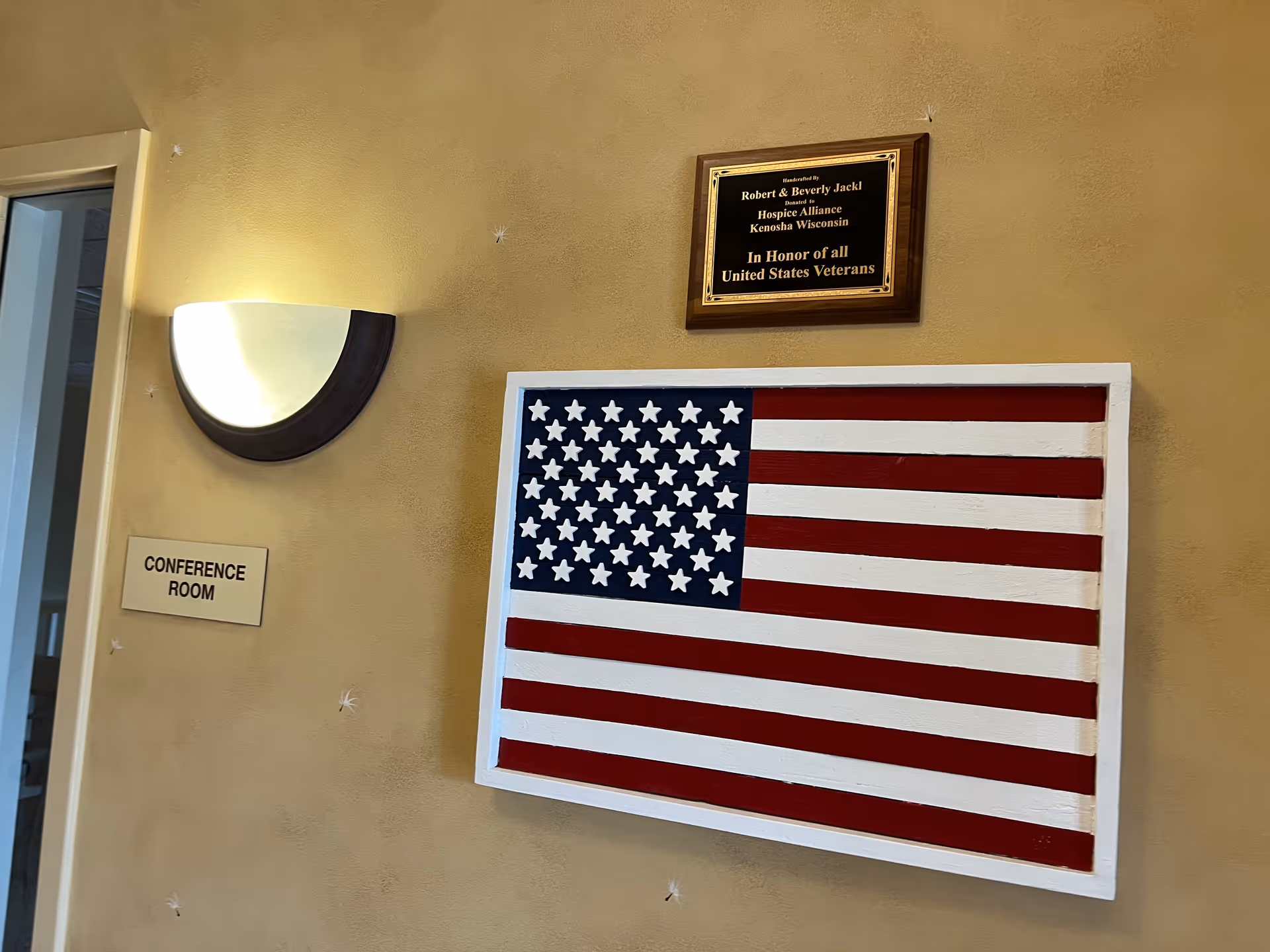 Hallway wall with conference room sign and framed American flag artwork.