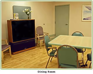 Dining room with table, chairs, TV cabinet, and a vase of flowers.
