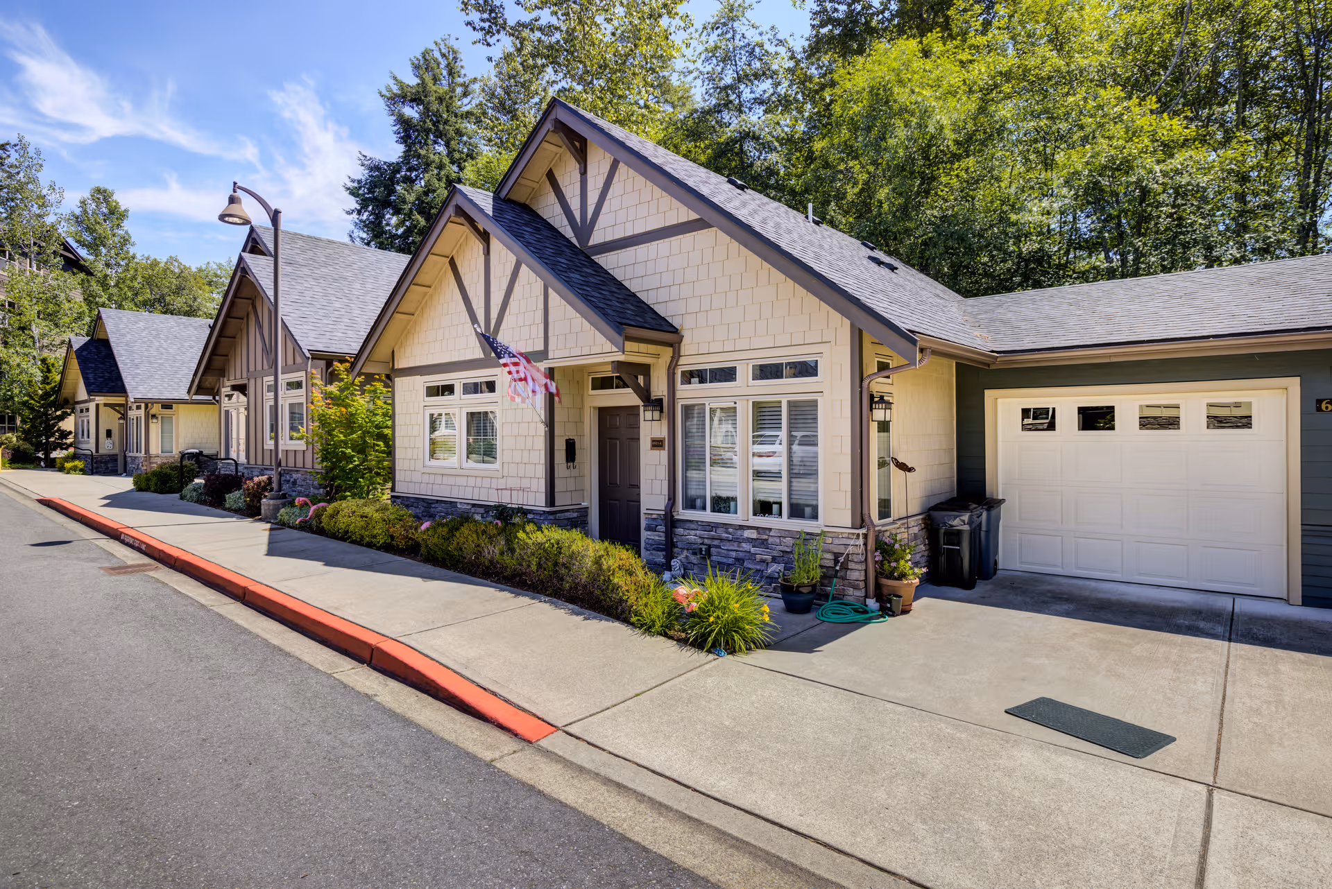 Exterior view of a senior living campus with stone accents and garages along a paved street