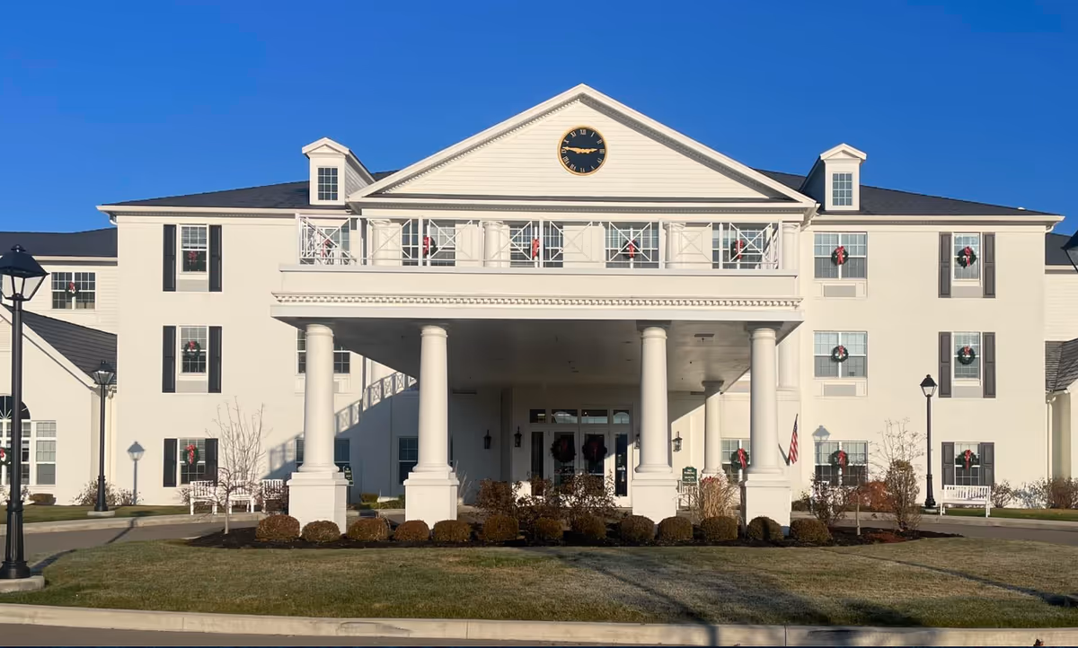 White multi-story senior living building with large columns at the entrance