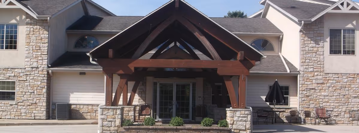 Exterior view of a senior living facility entry with stone walls and wooden front porch.