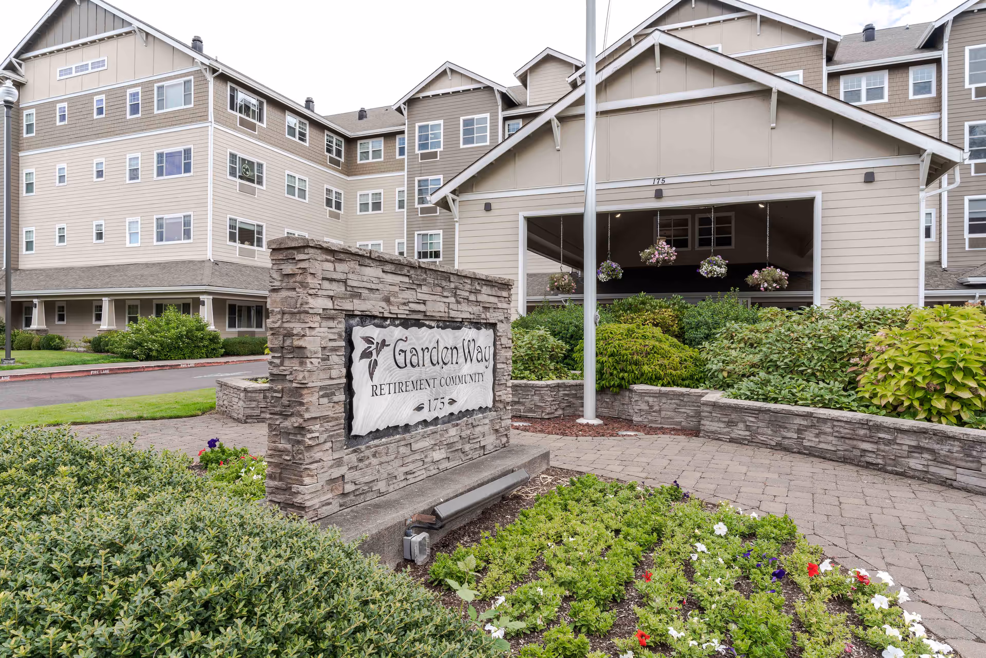 Exterior view of Garden Way Retirement Community with stone sign and landscaped entrance.