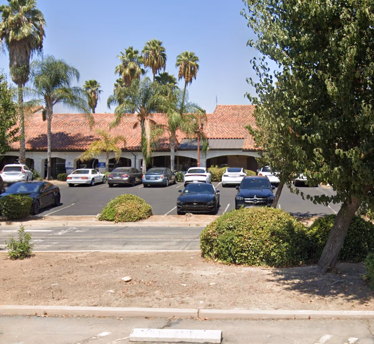 Exterior view of Home Instead facility in Fresno with a tile roof and palm trees.