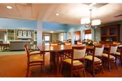 Spacious dining room with a large table, chairs, and warm lighting.