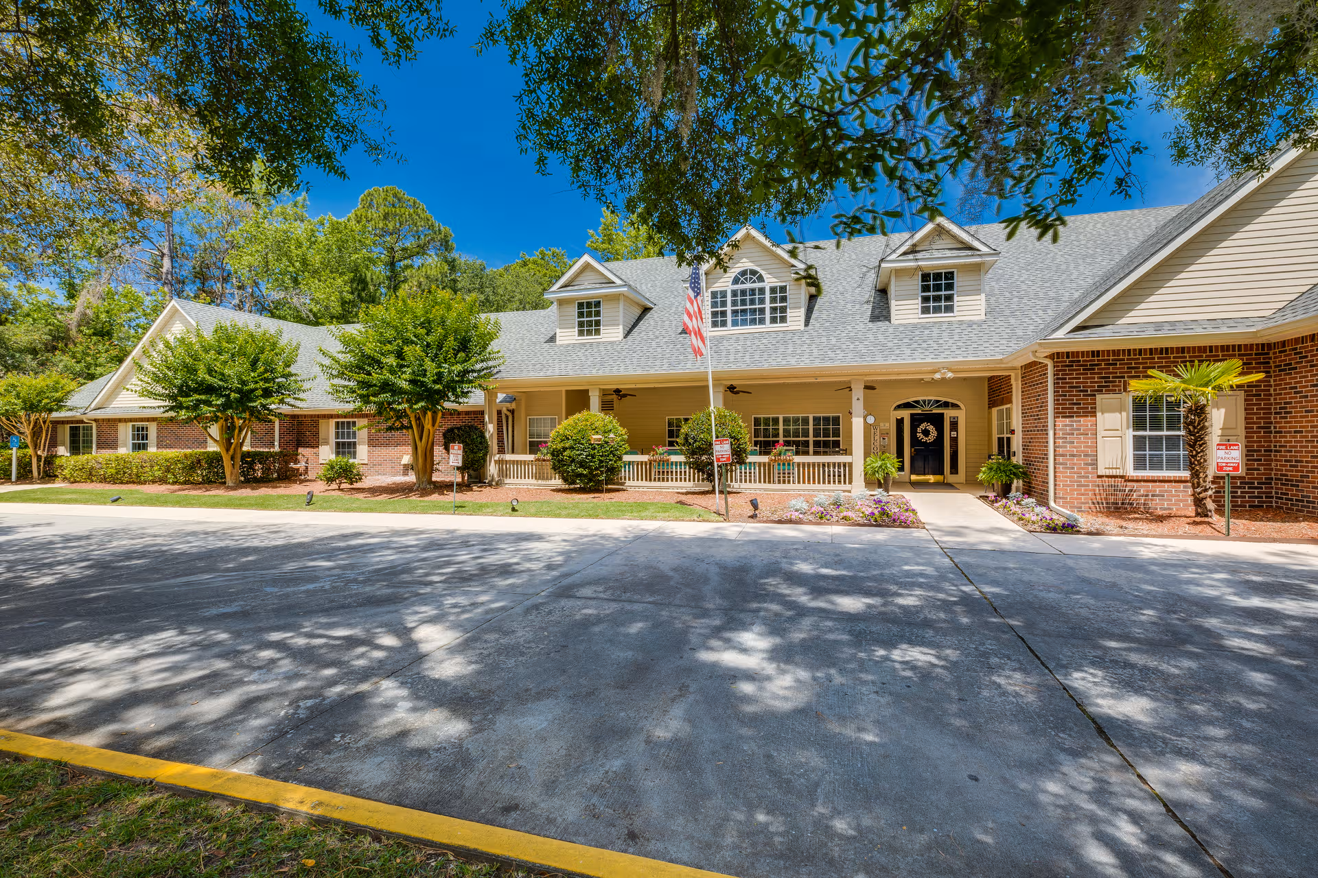 Front view of Village Cove Assisted Living building with entrance, flag, and landscaping