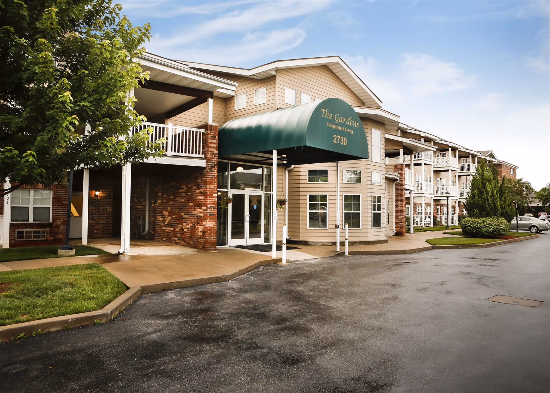 Exterior view of The Gardens senior living facility with entrance canopy and multiple balconies.