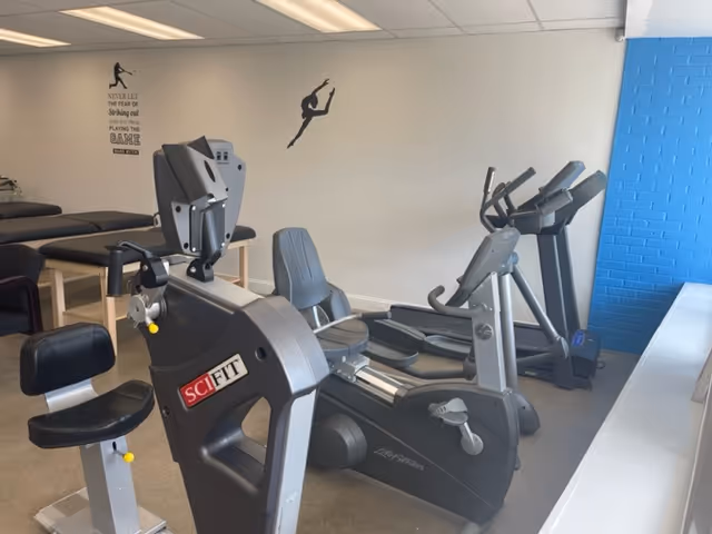 Indoor fitness room with multiple exercise machines and a blue accent wall.