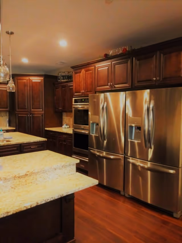 Modern kitchen with stainless steel appliances, dark wood cabinets, and granite countertops.