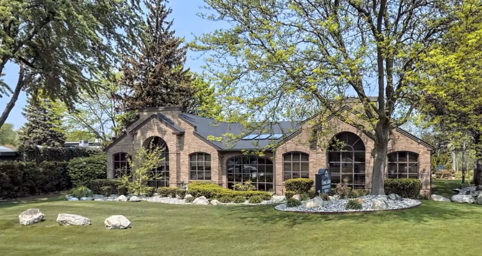 Sigma HomeCare facility exterior with brick walls, arched windows, and manicured landscaping.