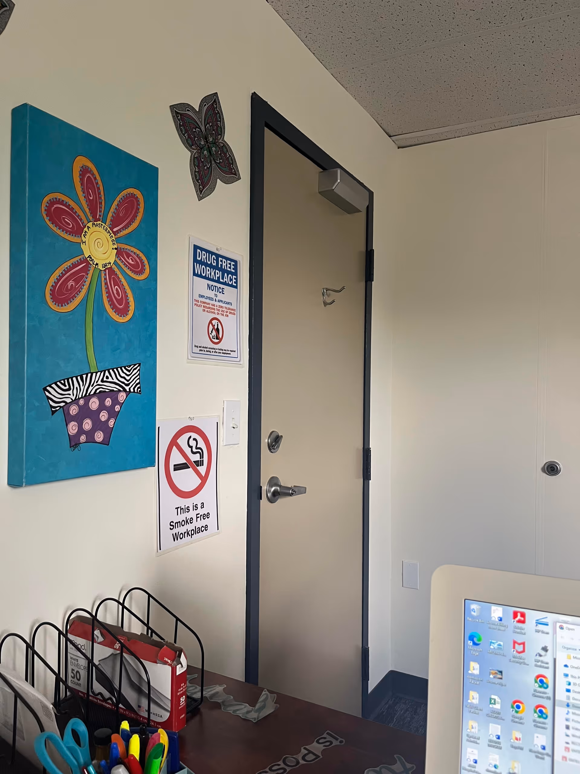 Interior hallway in Aroma Home Healthcare LLC with a closed door, wall art, and desk supplies.